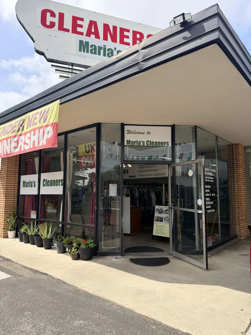 The glass front entrance of Maria's Cleaners under the rooftop sign